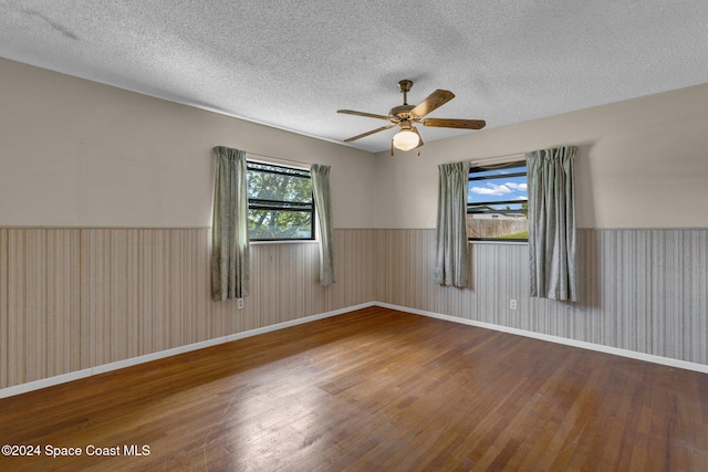 unfurnished room featuring a wealth of natural light, wood-type flooring, and a textured ceiling