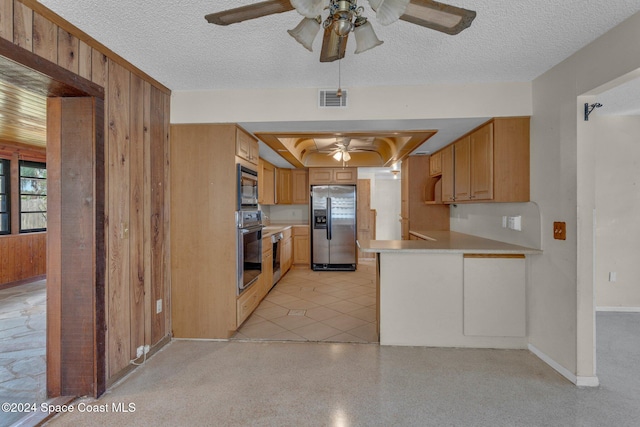 kitchen featuring stainless steel appliances, wooden walls, and a textured ceiling