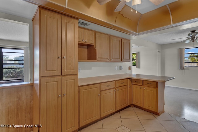 kitchen with ceiling fan, kitchen peninsula, a textured ceiling, and light tile patterned flooring