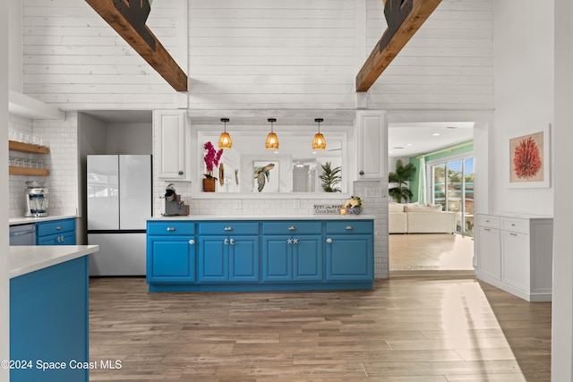 kitchen featuring beamed ceiling, refrigerator, pendant lighting, and light wood-type flooring