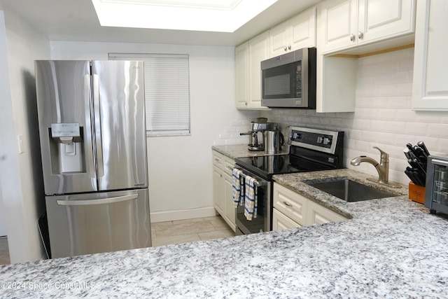 kitchen featuring stainless steel appliances, white cabinetry, sink, light stone counters, and tasteful backsplash