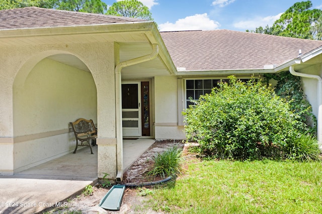 view of exterior entry featuring a patio area and a yard