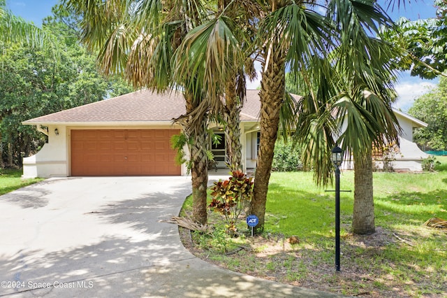 view of property hidden behind natural elements featuring a garage and a front yard