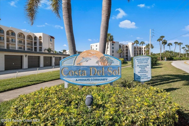 community sign featuring community garages and a lawn