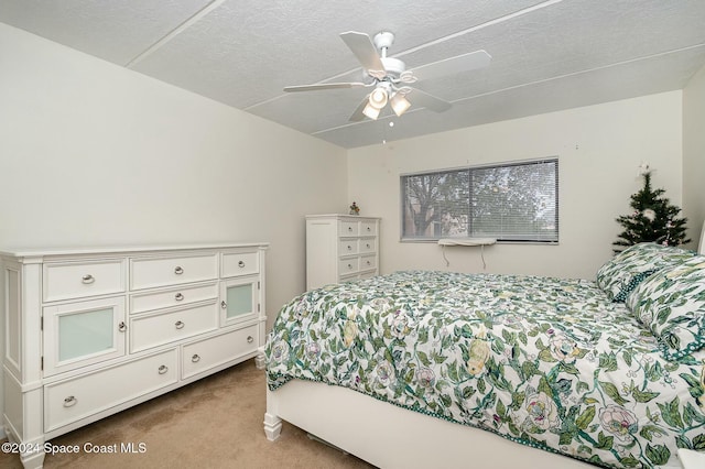 bedroom featuring a textured ceiling, light colored carpet, and ceiling fan