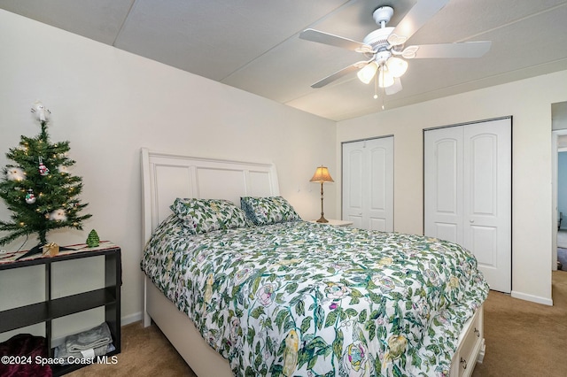 bedroom with carpet flooring, two closets, and ceiling fan