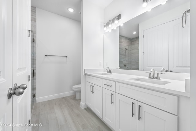 bathroom with vanity, hardwood / wood-style flooring, toilet, and a shower with shower door