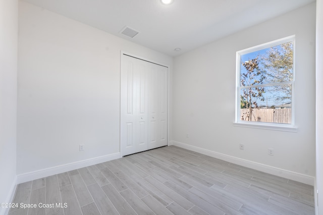 unfurnished bedroom with a closet and light hardwood / wood-style flooring