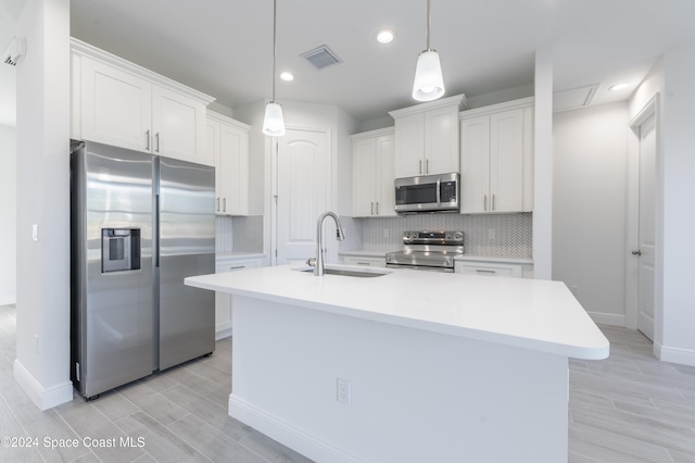 kitchen featuring sink, white cabinets, hanging light fixtures, and stainless steel appliances