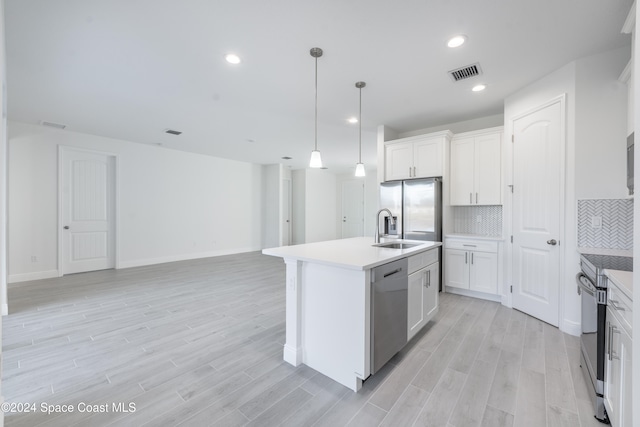 kitchen with white cabinetry, appliances with stainless steel finishes, decorative light fixtures, an island with sink, and light hardwood / wood-style floors