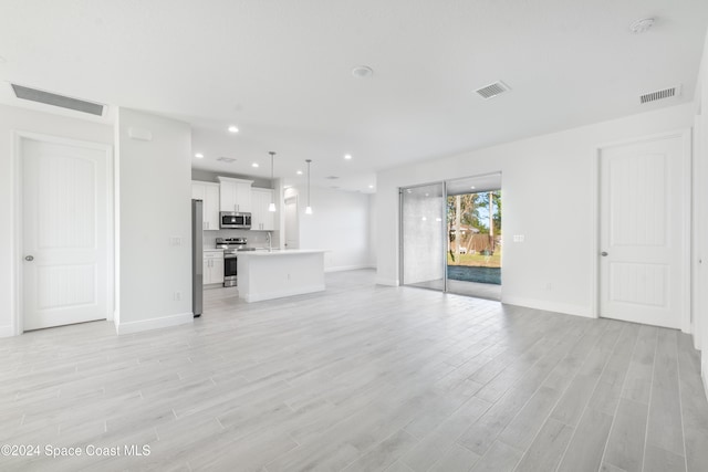 unfurnished living room with sink and light hardwood / wood-style flooring