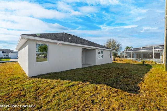 back of house featuring a lanai and a lawn