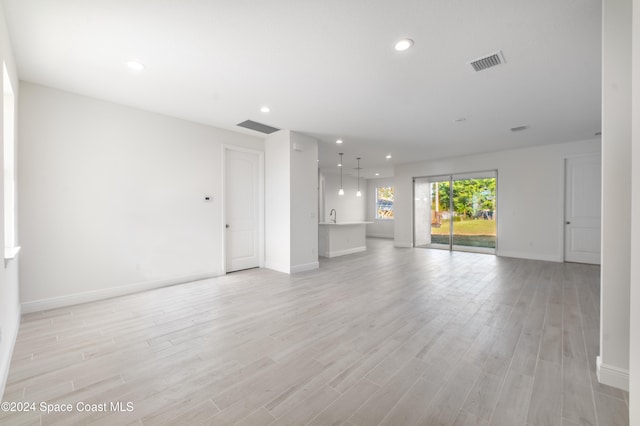 unfurnished living room featuring sink and light hardwood / wood-style floors