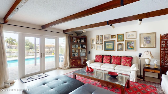 living room with french doors, a textured ceiling, and beam ceiling