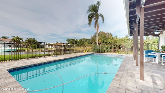 view of pool with a water view, ceiling fan, and a patio area