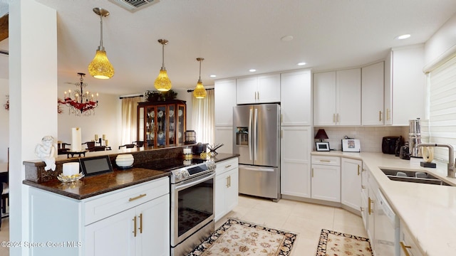 kitchen with sink, backsplash, decorative light fixtures, white cabinets, and appliances with stainless steel finishes