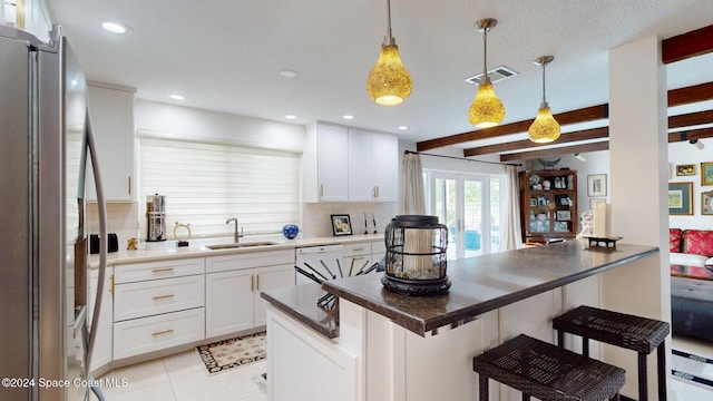 kitchen featuring a kitchen bar, stainless steel fridge, decorative light fixtures, beamed ceiling, and white cabinets