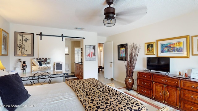 bedroom featuring a textured ceiling, a barn door, and ceiling fan