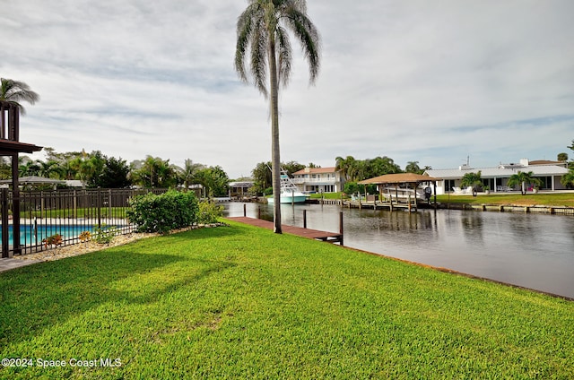 view of yard featuring a boat dock, a water view, and a fenced in pool