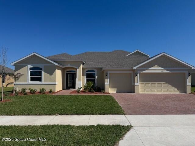 single story home with a front lawn, roof with shingles, stucco siding, decorative driveway, and a garage