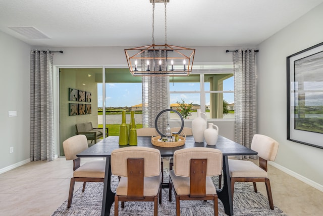 dining area with light tile patterned flooring, a textured ceiling, and a chandelier