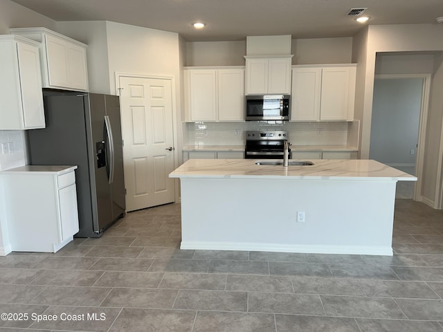 kitchen featuring sink, a center island with sink, stainless steel appliances, decorative backsplash, and white cabinets