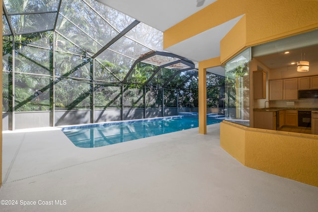 view of swimming pool featuring glass enclosure, sink, and a patio area