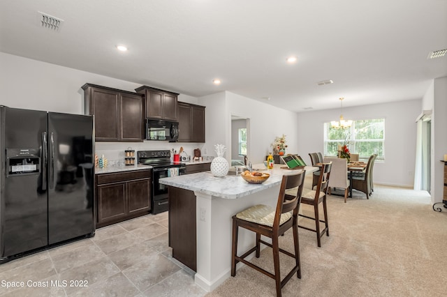 kitchen featuring dark brown cabinetry, a center island with sink, light carpet, black appliances, and a kitchen bar