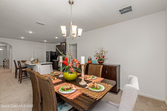 carpeted dining room with a notable chandelier and a textured ceiling