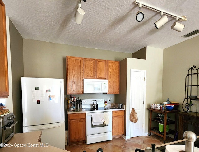 kitchen featuring a textured ceiling, light tile patterned flooring, white appliances, and rail lighting