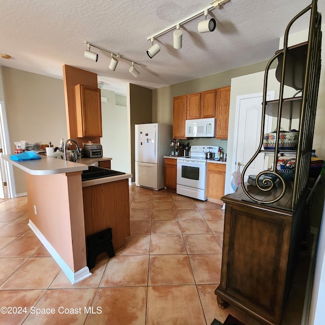 kitchen featuring kitchen peninsula, light tile patterned floors, track lighting, and white appliances