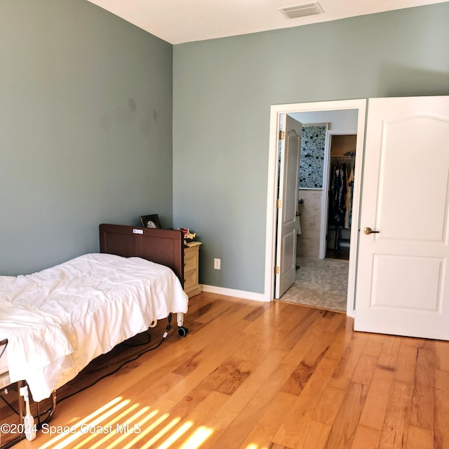 bedroom with a walk in closet, light wood-type flooring, and a closet