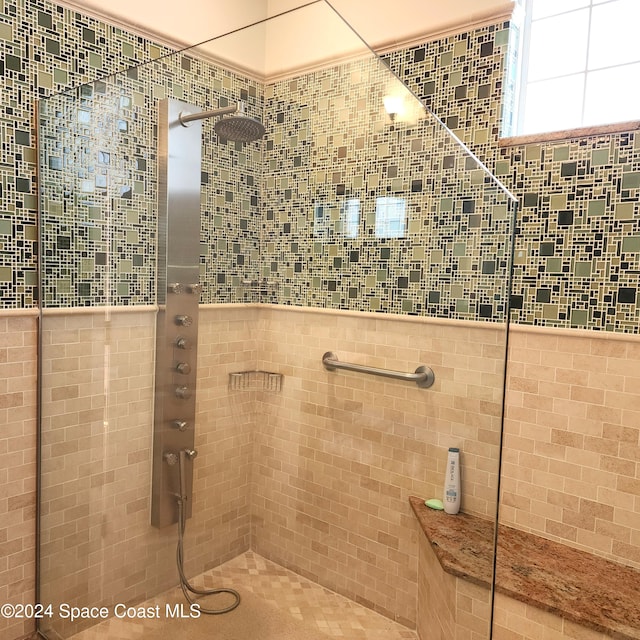 bathroom with a tile shower and tile walls