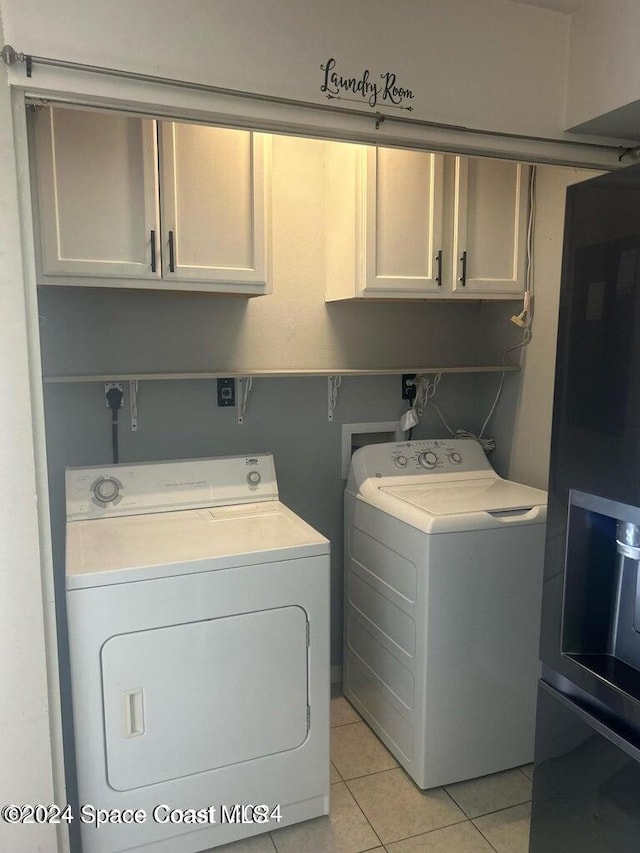 washroom with washing machine and clothes dryer, cabinets, and light tile patterned flooring