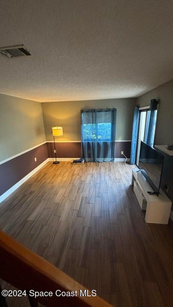 unfurnished living room featuring a textured ceiling, hardwood / wood-style flooring, and a wealth of natural light