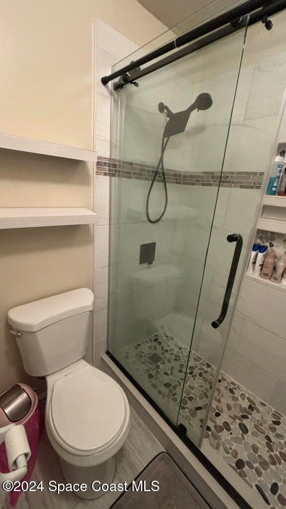 bathroom with toilet and a shower with door