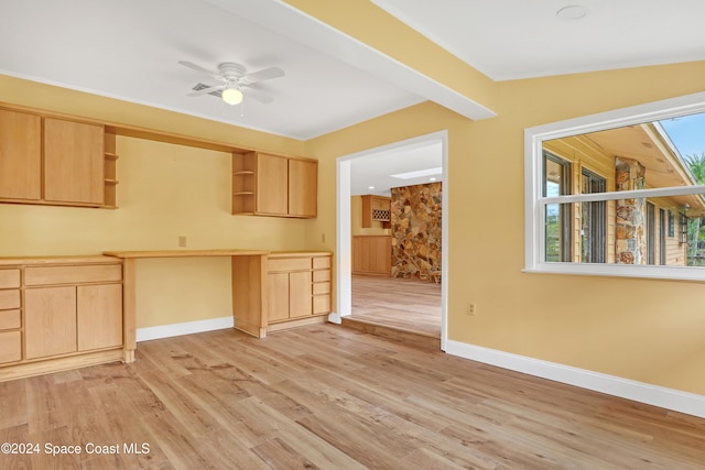 kitchen with a healthy amount of sunlight, light brown cabinets, built in desk, and light hardwood / wood-style flooring