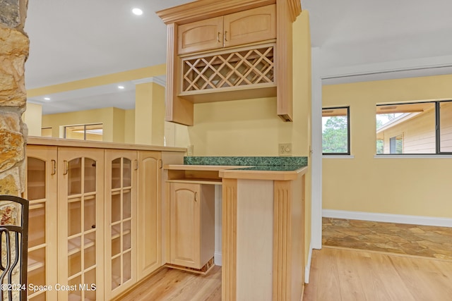 bar with light brown cabinetry and light hardwood / wood-style flooring