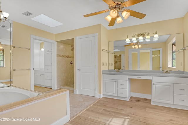 bathroom featuring a skylight, vanity, shower with separate bathtub, ceiling fan, and hardwood / wood-style floors