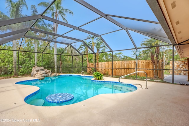 view of swimming pool featuring glass enclosure and a patio