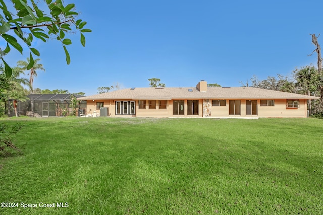 rear view of property with a lanai and a yard