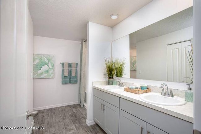 bathroom with hardwood / wood-style floors, vanity, and a textured ceiling