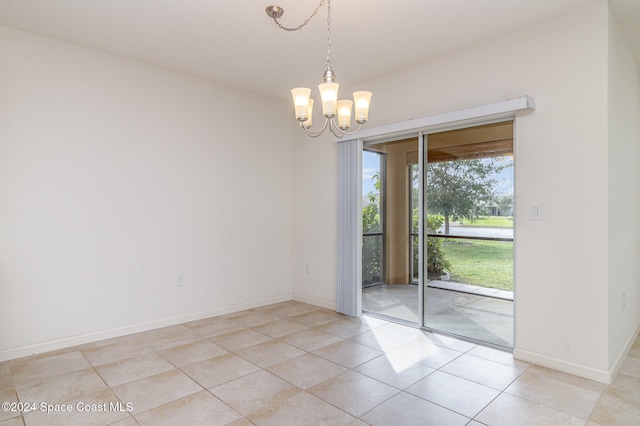 tiled spare room featuring an inviting chandelier