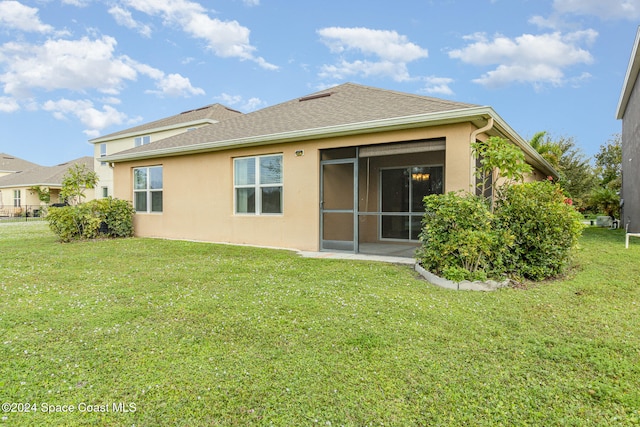 rear view of property with a lawn and a sunroom