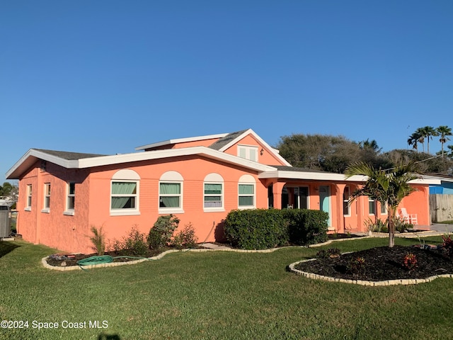 view of front of home with central AC unit and a front lawn