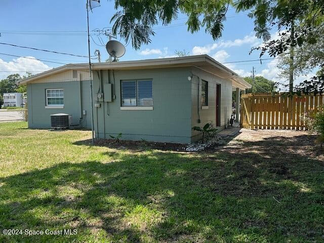 rear view of property with a lawn and cooling unit