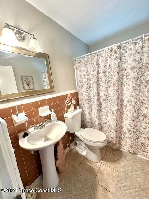 bathroom featuring tile patterned floors, sink, tile walls, and toilet