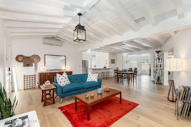 living room featuring vaulted ceiling with beams, a wall mounted AC, light hardwood / wood-style floors, washer / dryer, and a chandelier