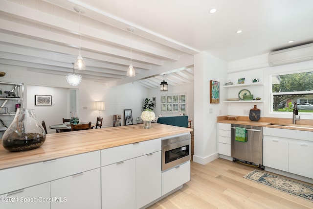 kitchen with sink, hanging light fixtures, appliances with stainless steel finishes, butcher block countertops, and white cabinetry