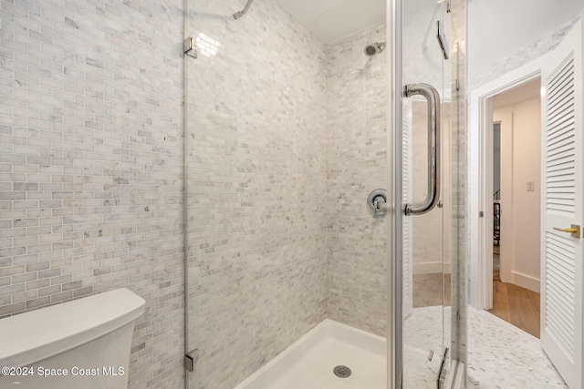 bathroom featuring wood-type flooring, toilet, and an enclosed shower